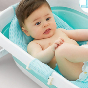 A baby secured in the detachable cradle of a KidEasy bathtub, enjoying bath time safely.